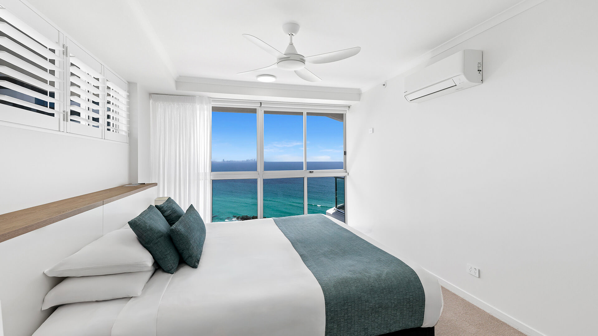 Main bedroom in the Deluxe 3 Bedroom Ocean View Apartment at ULTIQA Points North, featuring a king bed, coastal décor, and panoramic ocean views.