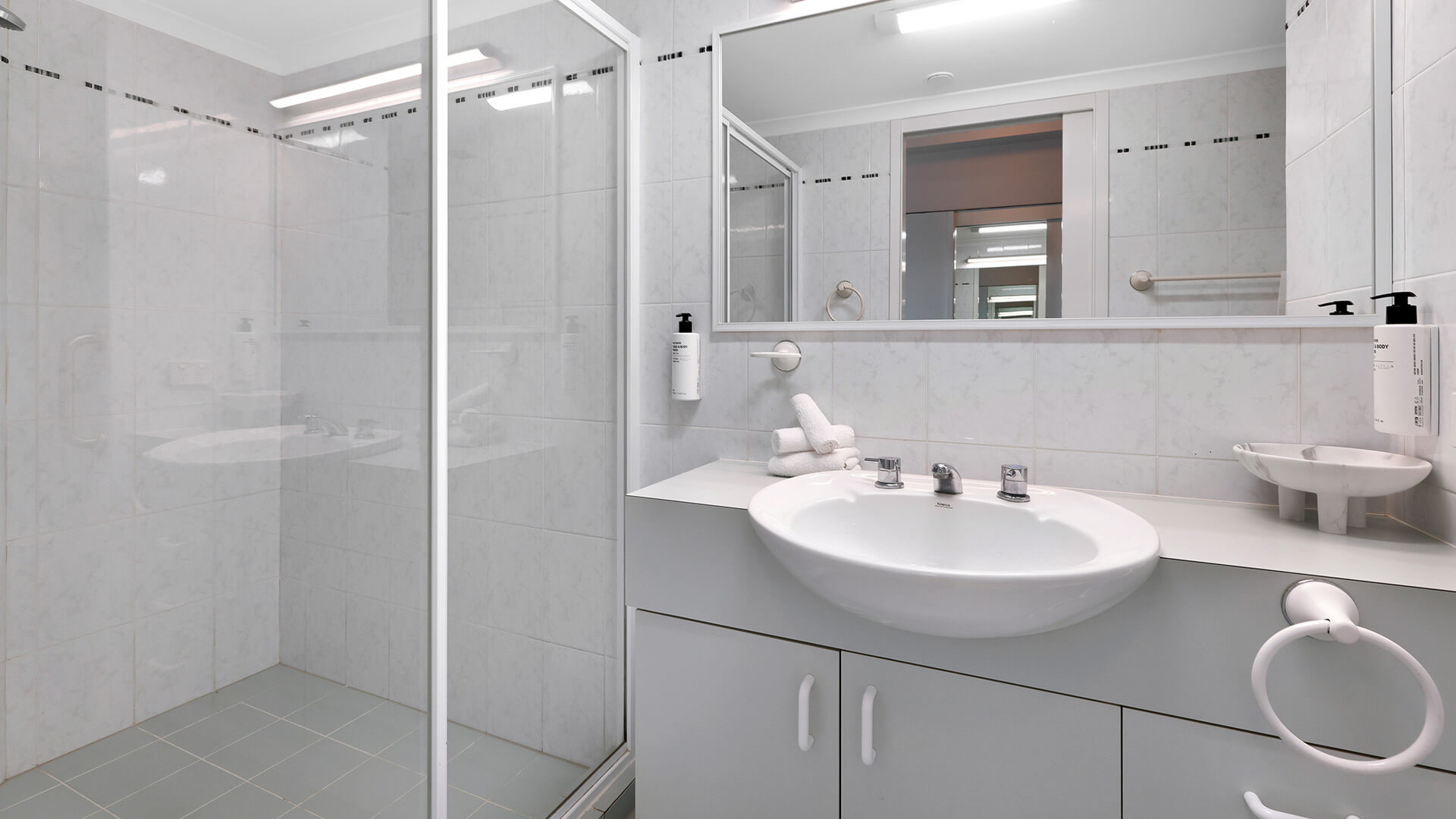 Bathroom in the Standard 2 Bedroom Centre Front Apartment featuring a walk-in shower and ample vanity space.