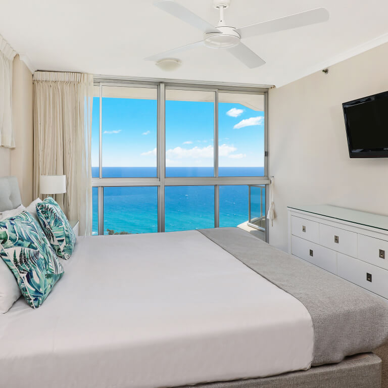 Bedroom at ULTIQA Points North featuring a king bed, modern coastal décor, and floor-to-ceiling windows with panoramic ocean views.