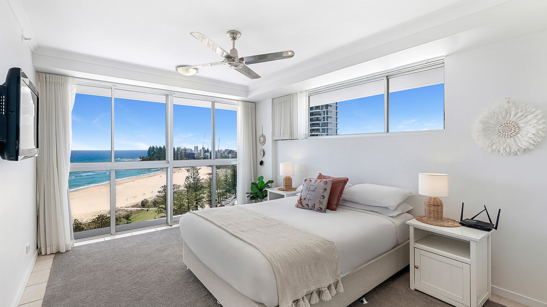 Master bedroom in the 2 Bedroom Superior Ocean View Apartment featuring a queen bed, soft neutral décor and large windows with sweeping ocean views.