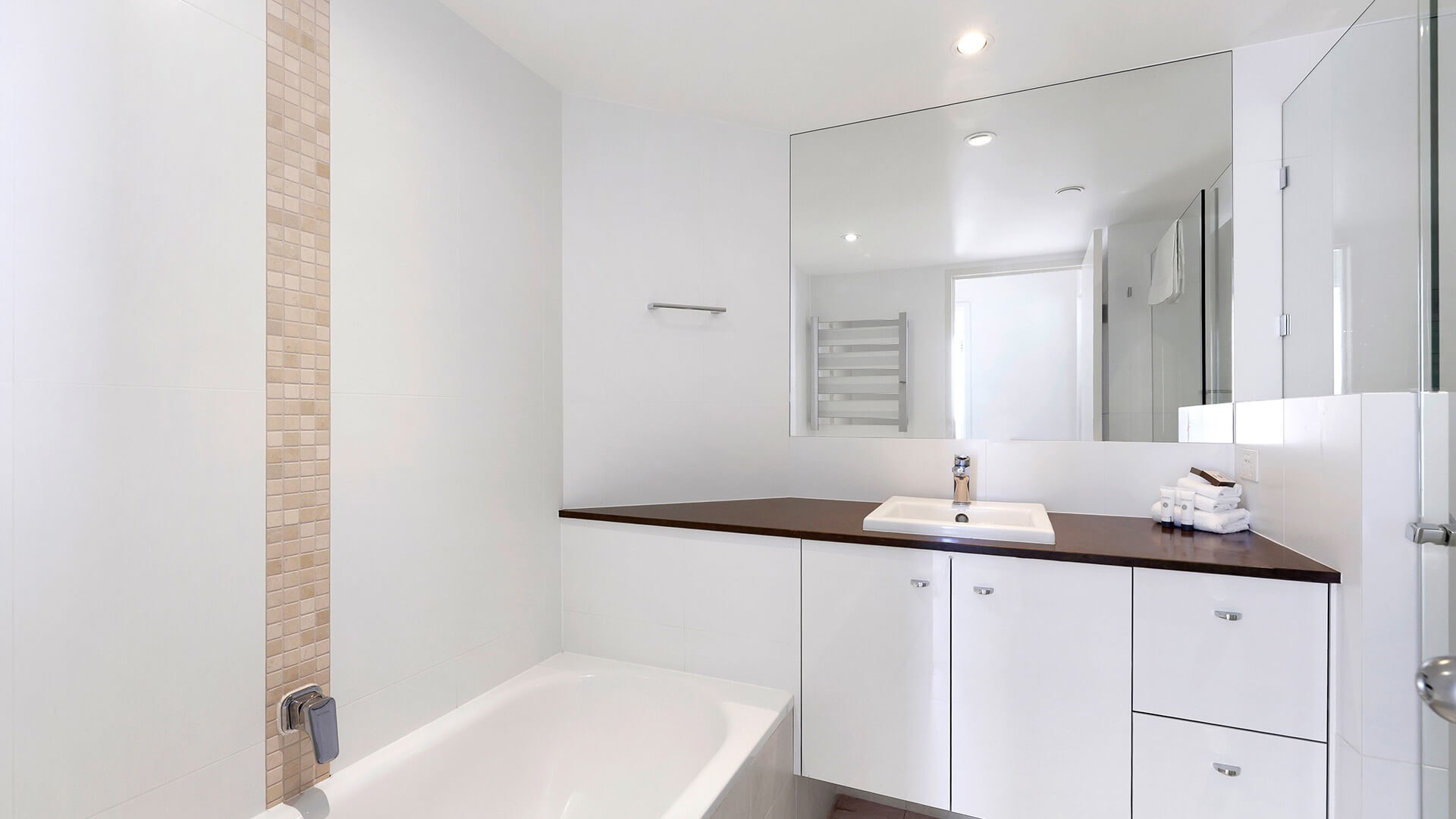 Bathroom in the Superior 3 Bedroom Ocean View Apartment featuring a bathtub, large mirror, and modern vanity with ample counter space.