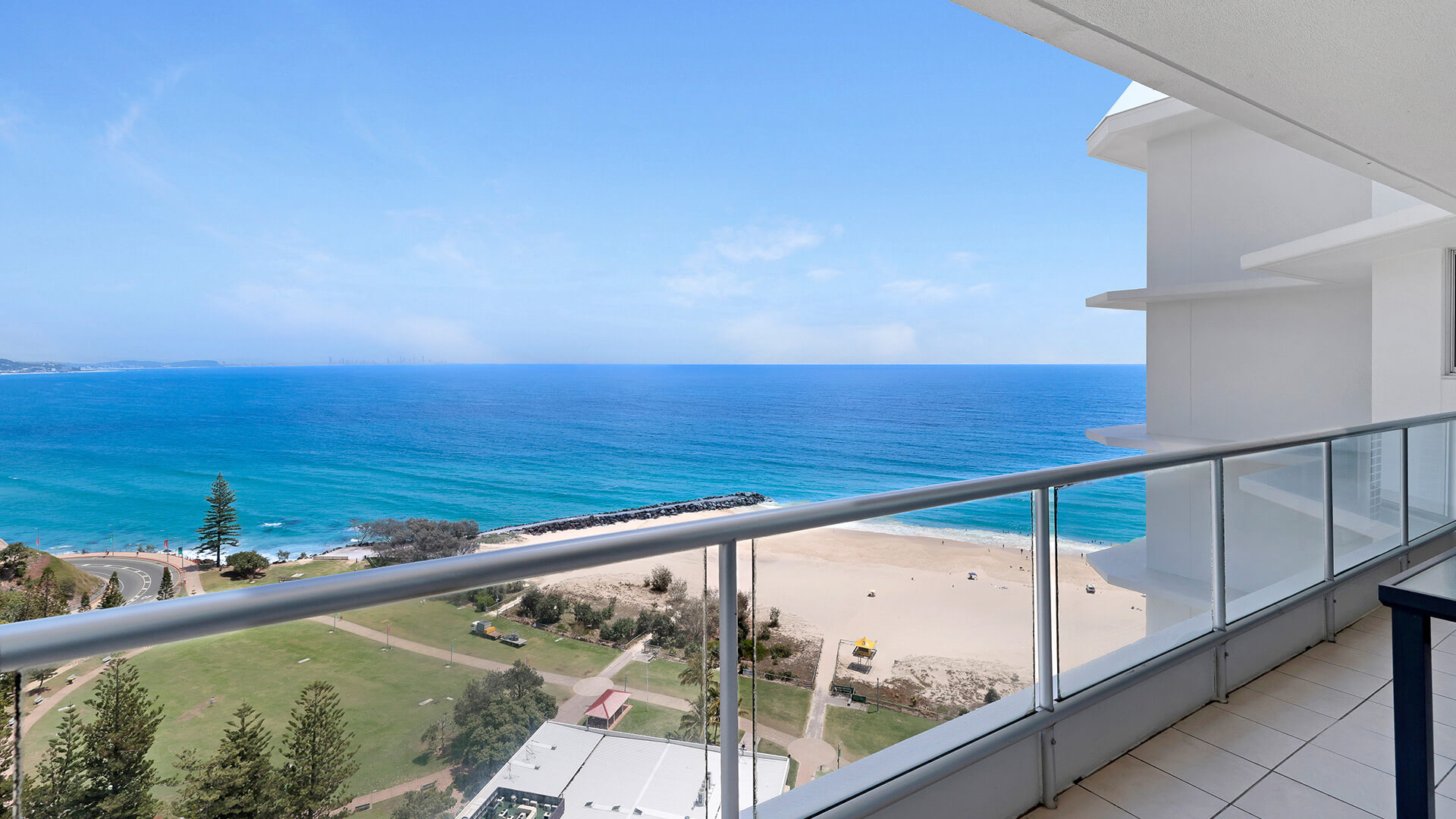 Private balcony of the Superior 3 Bedroom Ocean View Apartment overlooking the beach, parkland, and turquoise ocean.