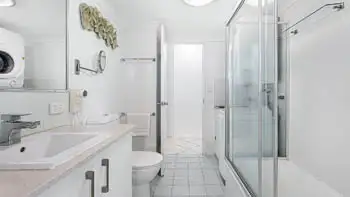 2nd bathroom in a 2 Bedroom Superior Ocean View Apartment with vanity, toilet, shower-over-bath with glass screens, in-room laundry, washer & dryer.